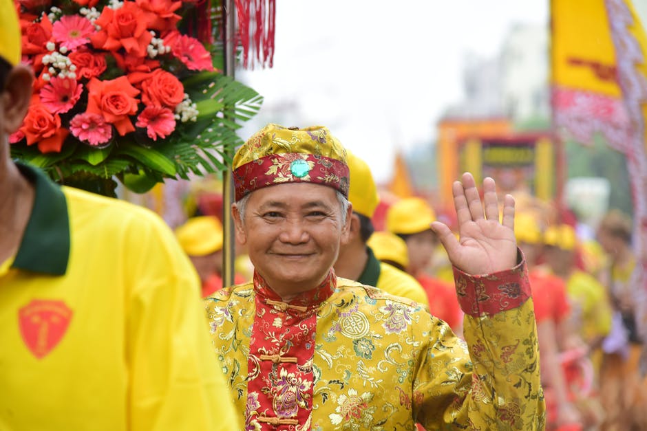 Smiling elderly man waving during a vibrant cultural festival parade in traditional attire